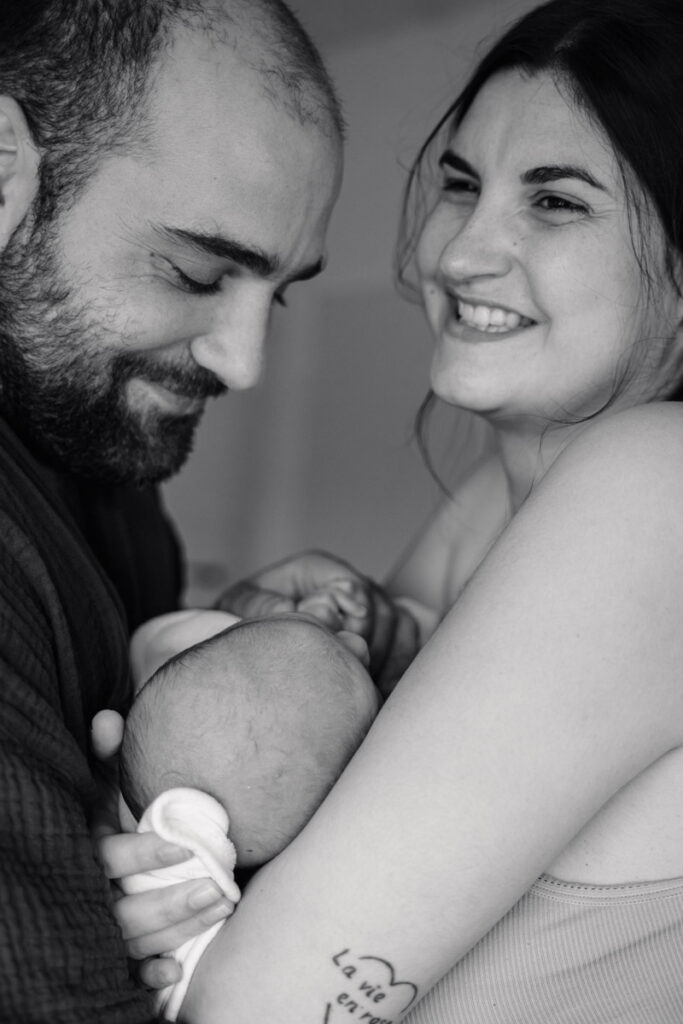 photo de deux parents en noir et blanc tenant leur nouveau né dans les bras dans une chambre de maternité à Pessac