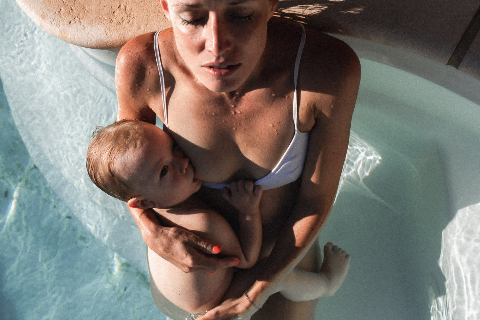 Séance photo allaitement à Bordeaux avec une mère allaitant son bébé dans une piscine