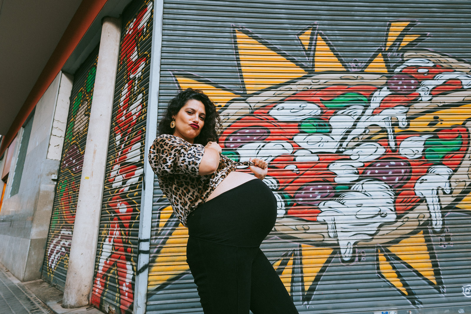 Photographe maternité à Bordeaux enceinte posant devant une fresque colorée dans un environnement urbain