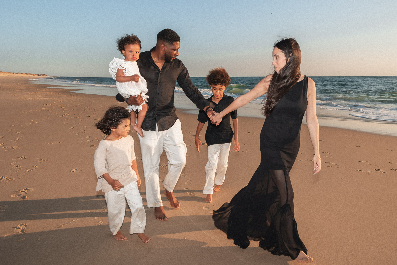 Famille avec trois enfants marchant sur la plage au coucher du soleil photographe maternité bordeaux
