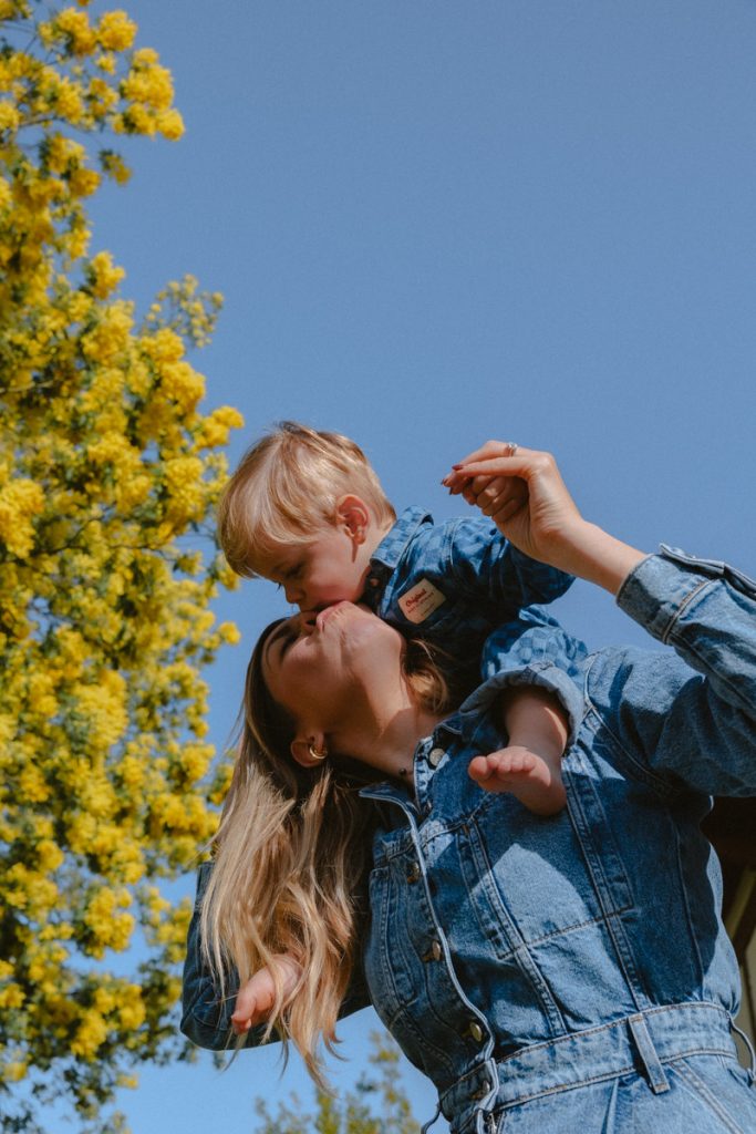 maman avec son fils sur les épaules à côté d'un mimosa