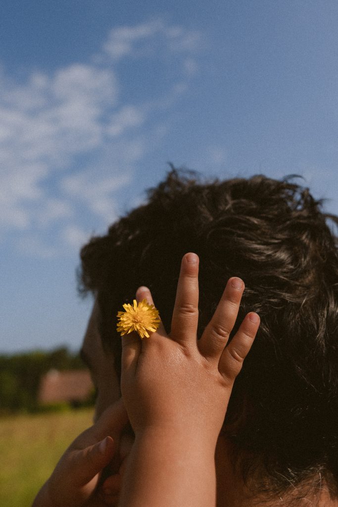 séance photo famille La Brède, enfant déposant une fleur dans les cheveux de son papa